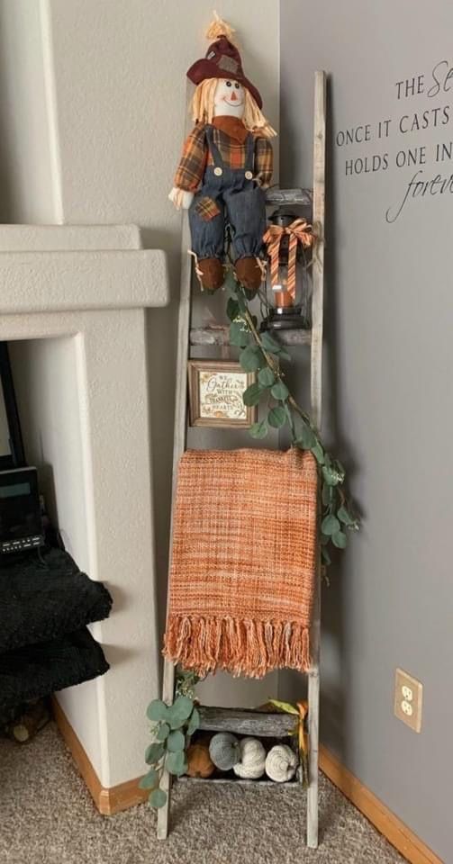 A cozy ladder adorned with a friendly scarecrow and a plush blanket, creating a charming display of warmth and whimsy.