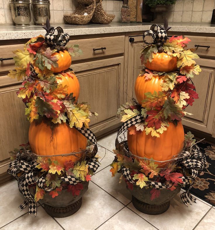 Two festive pumpkin topiaries adorned with autumn leaves and charming bows, adding a touch of seasonal elegance.